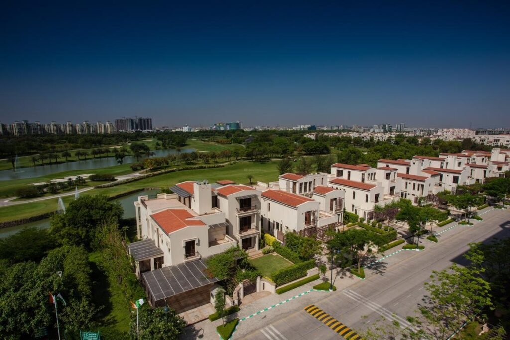 Aerial view of luxury villas with red-tiled roofs, landscaped gardens and a green waterfront
